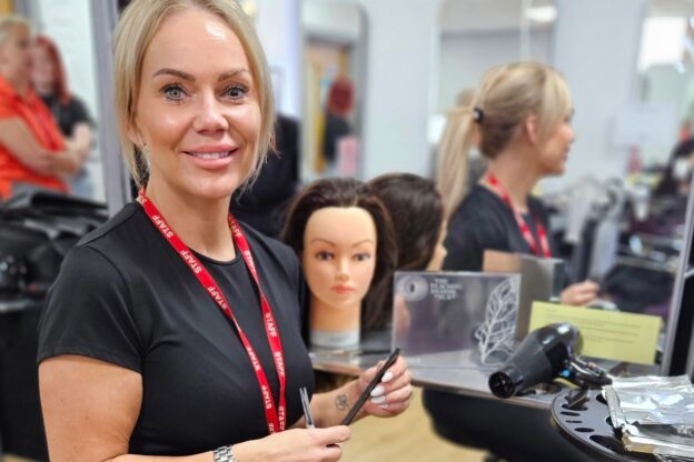 Lisa Charles stands with a pair of hairdressing scissors and her Silver Pearson Award.